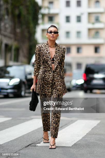 Guest wears sunglasses, a golden chain necklace, bras, a brown leopard print oversized blazer jacket, suit pants, a fluffy black bag, shoes, outside...