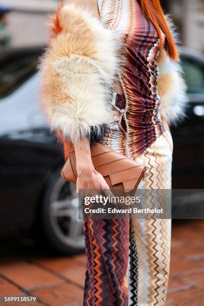 Guest wears a fluffy colored jacket, a gathered turtleneck colored top with geometric patterns, flared pants, a brown leather bag, outside Missoni,...