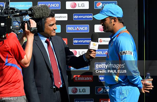 India's captain Mahendra Singh Dhoni gives a TV interview following the warm-up cricket match ahead of the 2013 ICC Champions Trophy between India...