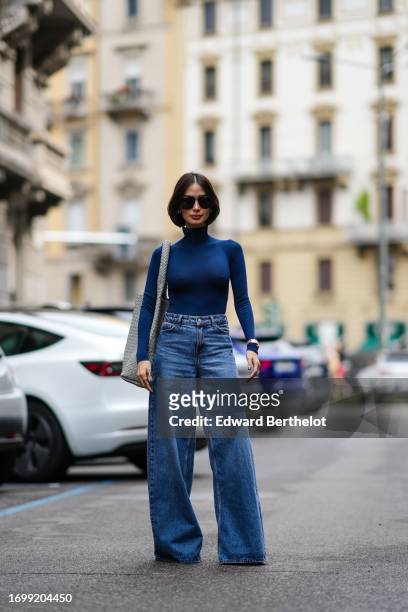 Heart Evangelista wears a blue turtleneck top, a gray woven leather large bag from Bottega Veneta, blue flared denim jeans / pants, during the Milan...