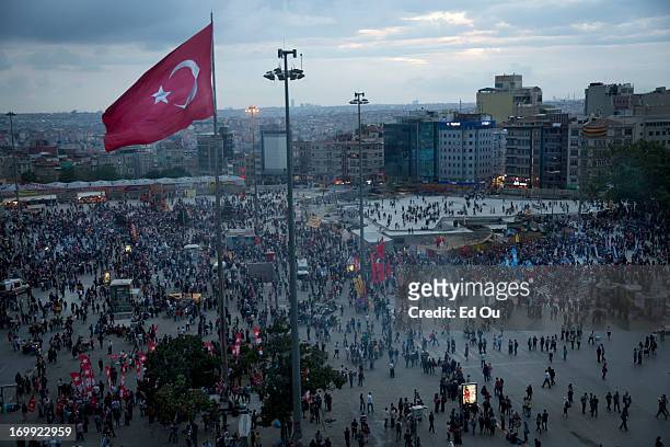 Protesters and onlookers stand on the roof of the Atatürk Cultural Center looking down at an anti-government protest rally in Taksim Square in...