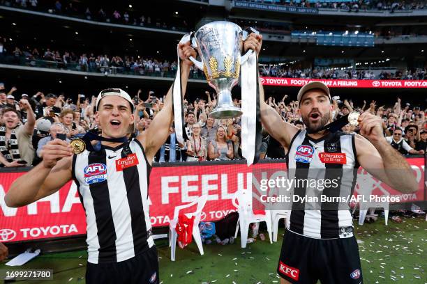 Nick Daicos and Steele Sidebottom of the Magpies celebrate with the premiership cup during the 2023 AFL Grand Final match between the Collingwood...