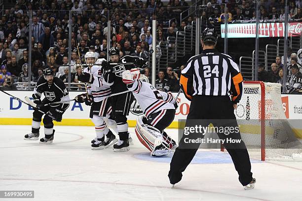 Dustin Brown of the Los Angeles Kings deflects the puck in front of goaltender Corey Crawford of the Chicago Blackhawks as referee Stephen Walkom...