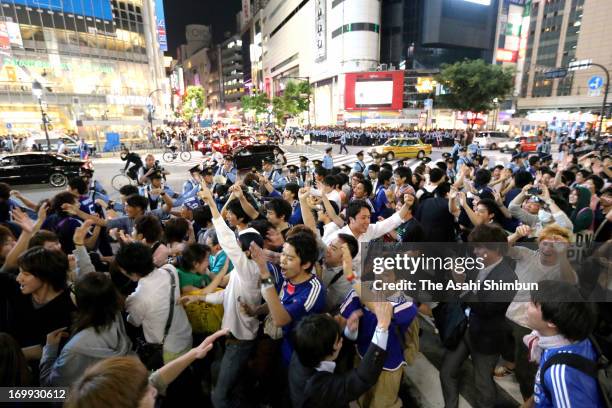 Supporters celebrate as Japan football national team qualified for the FIFA World Cup Brazil while police officers control the traffic at Shibuya...