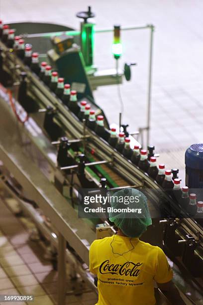 An employee monitors operations as bottles of Coca-Cola soda move along the production line at the Coca-Cola Co. Bottling plant in Hmawbi, Myanmar,...