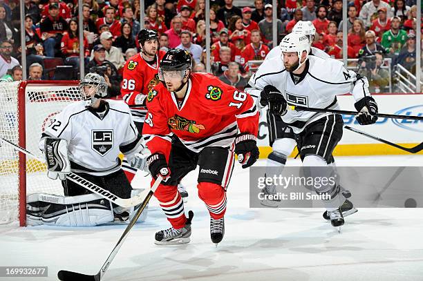 Marcus Kruger of the Chicago Blackhawks and Davis Drewiske of the Los Angeles Kings skate after the puck in front of goalie Jonathan Quick of the Los...