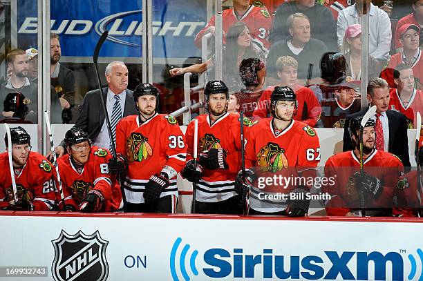 Dave Bolland, Marcus Kruger and Michael Frolik of the Chicago Blackhawks stand in the bench in front of head coach Joel Quenneville in Game One of...