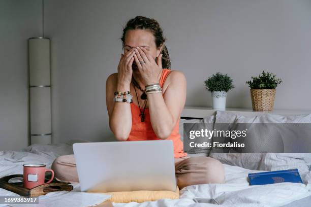 portrait of a woman with laptop sitting on the bed - staring at screen stock pictures, royalty-free photos & images