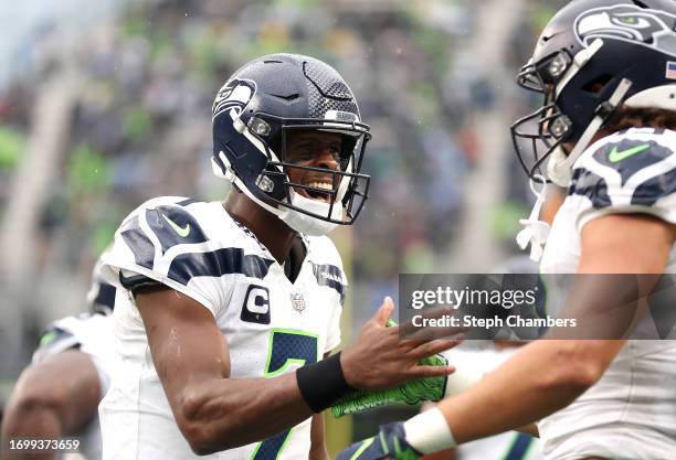 Geno Smith of the Seattle Seahawks celebrates with Jake Bobo of the Seattle Seahawks after Bobo's receiving touchdown during the fourth quarter...