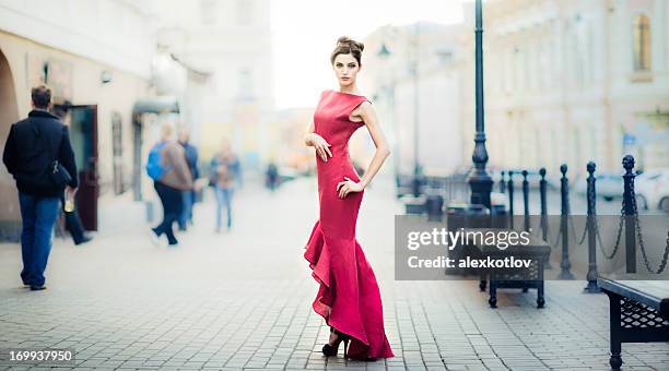 young woman in red dress on city streets - evening gowns stock pictures, royalty-free photos & images