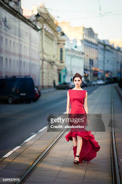 young woman in red dress on city streets - woman in evening gown stock pictures, royalty-free photos & images