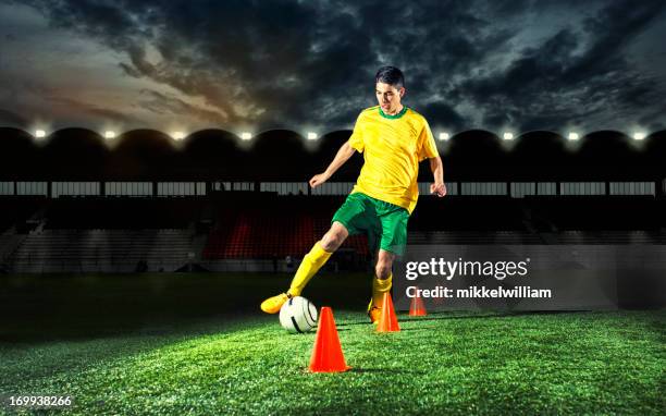 soccer player is training with plastic cones at night - kegel exercise stockfoto's en -beelden