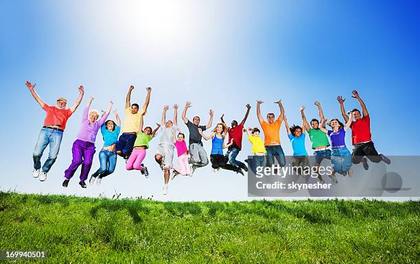 large group of people jumping against the clear sky. - kids smiling multiple nationalities stock pictures, royalty-free photos & images