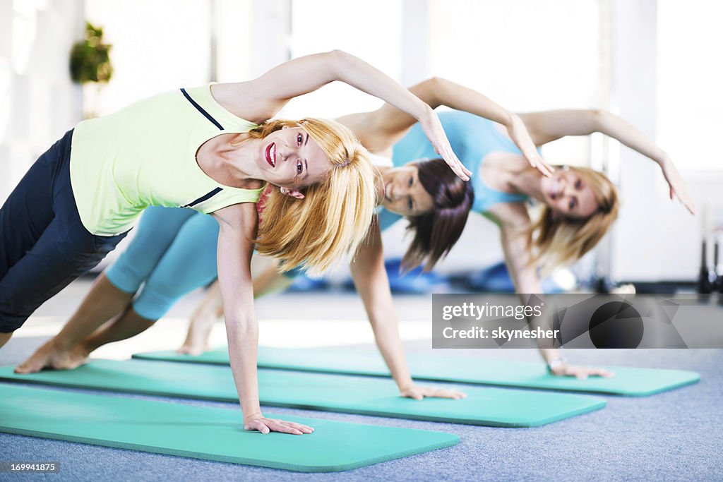 Cheerful adult women doing stretching exercises on Pilates class