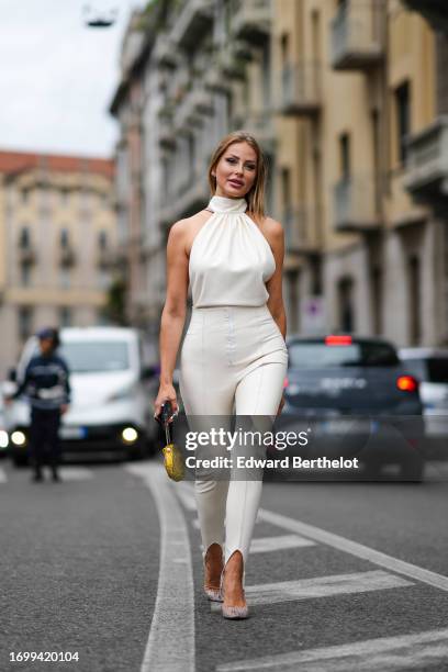 Guest wears a sleeveless turtleneck gathered top, white stirrup leggings, outside Philosophy Di Lorenzo, during the Milan Fashion Week - Womenswear...