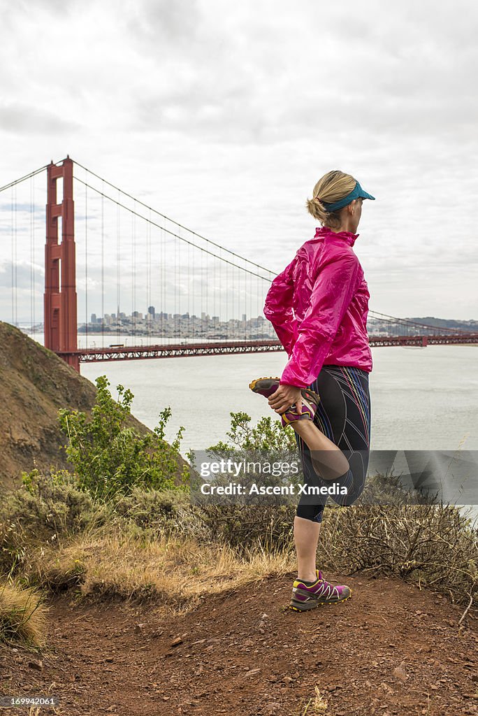 Woman stretches before trail running, Golden Gate
