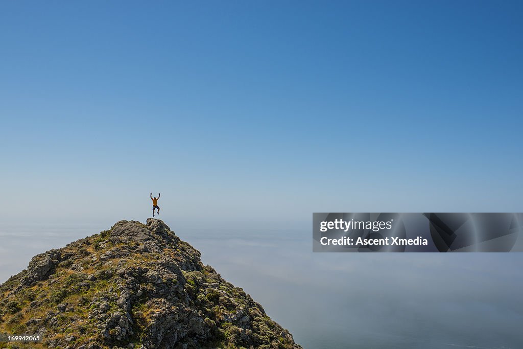 Distant man jumps from hill crst, exhilarated