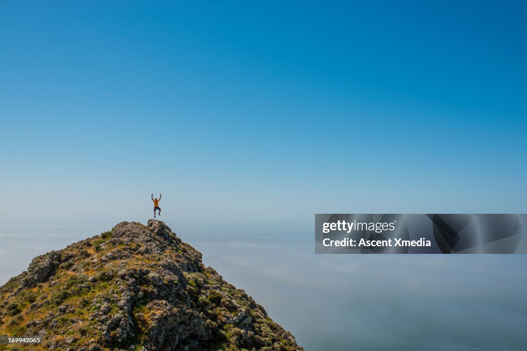 Distant man jumps from hill crst, exhilarated