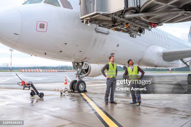 two mixed race male air controllers doing an inspection on the field - passenger boarding bridge stock pictures, royalty-free photos & images