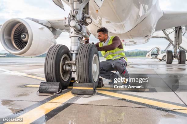 uomo di razza mista che fa un controllo su un aereo - mezzo di trasporto aereo foto e immagini stock