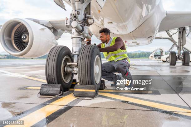 uomo di razza mista che fa un controllo su un aereo - airport ground crew foto e immagini stock