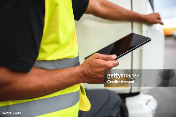 mid adult mixed race airport worker using digital tablet - grounds crew stock pictures, royalty-free photos & images
