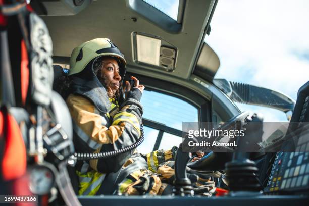 vigile del fuoco femminile che utilizza una stazione cb in un camion dei pompieri - firefighters foto e immagini stock