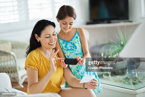 girl and mother using smart phone to deposit check - cheque deposit stock pictures, royalty-free photos & images