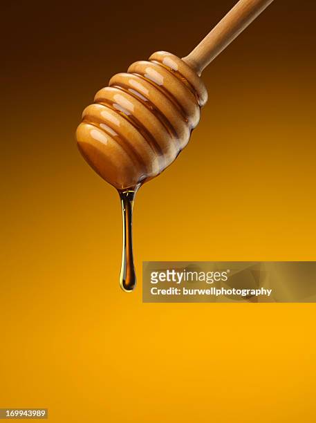 organic honey with wooden dipper - honinglepel stockfoto's en -beelden
