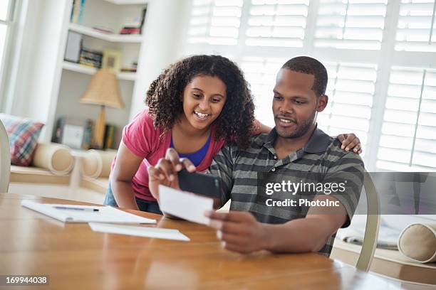 daughter and father paying bill using mobile phone - cheque deposit stock pictures, royalty-free photos & images