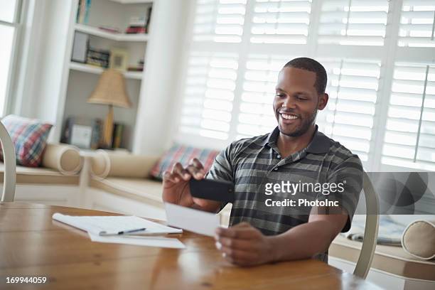 a man using his smartphone to deposit his check - deposit slip stock pictures, royalty-free photos & images