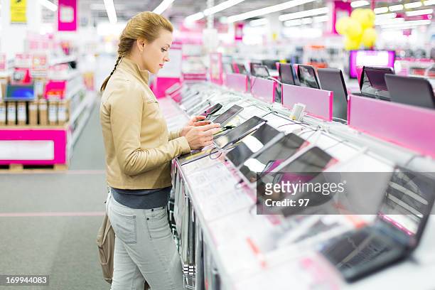 mujer compra una tableta digital. - electronic fotografías e imágenes de stock