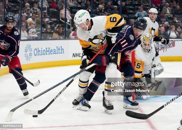 Mark Pysyk of the Pittsburgh Penguins and Adam Fantilli of the Columbus Blue Jackets battle for the puck during the second period at Nationwide Arena...