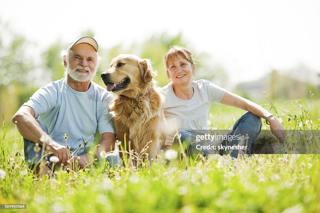 Two elderly people with their dog in the park.