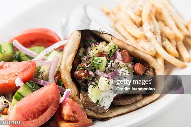 a close-up of a gyro pita sandwich with a salad and fries. - doner kebab stockfoto's en -beelden