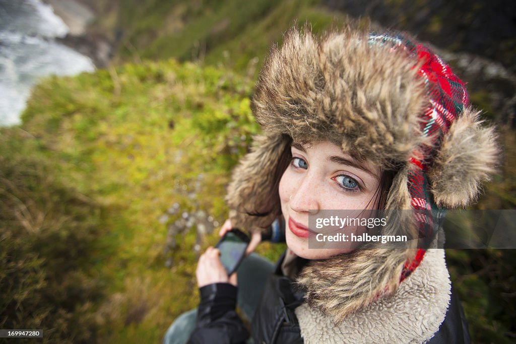 Hiker Girl in a Fur Hat on top of Cliff