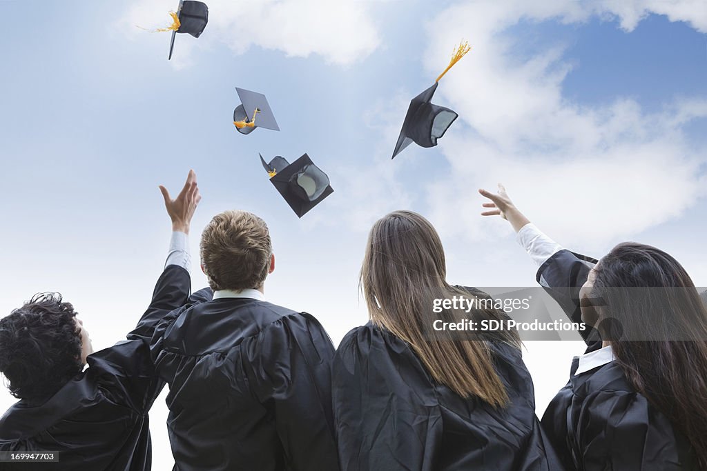 Excited group of college graduates throwing their hats in celebration