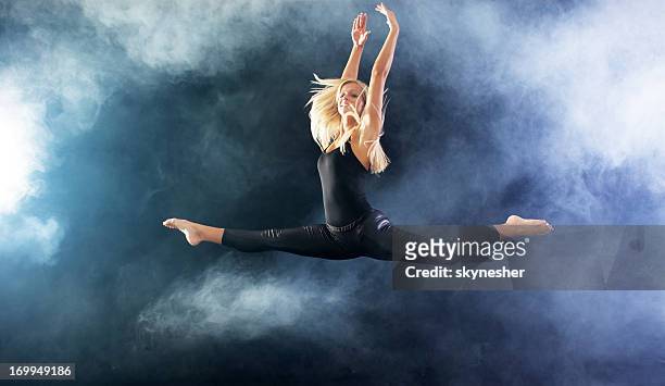 blonde woman jumping through the fog. - jazz dancing stock pictures, royalty-free photos & images