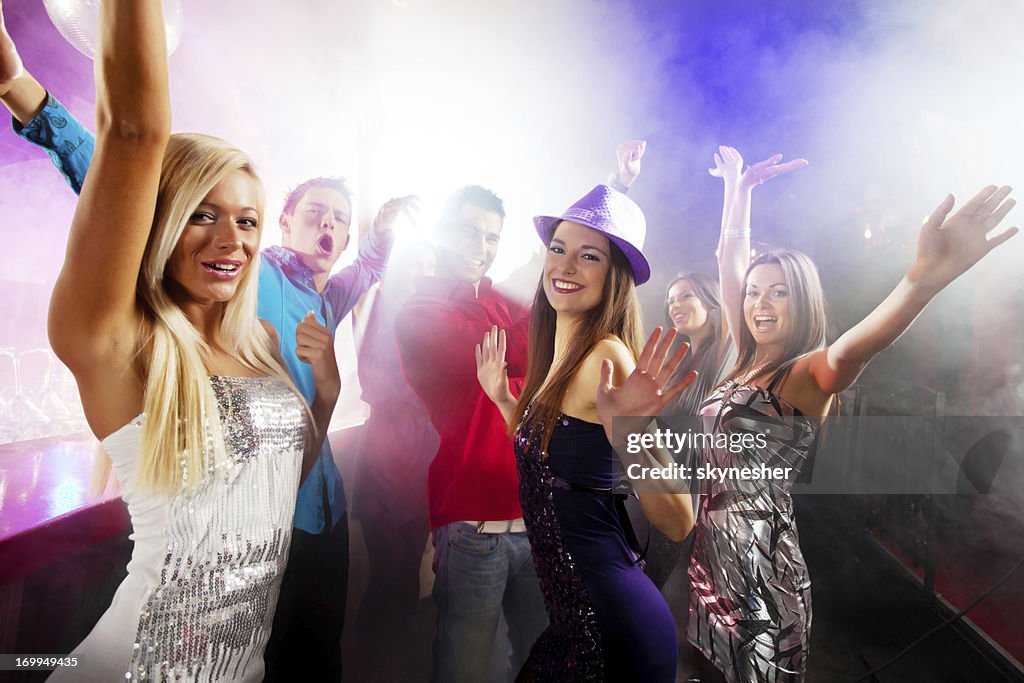 Young people dancing with their arms raised.