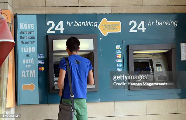 Young man tries to get money on bank in Nicosia on May 25, 2013 in Nicosia, Cyprus. Cyprus is continuing to struggle with the aftermath of its bank...