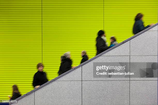 civilians riding an escalator with a green screen background - bende menigte stockfoto's en -beelden