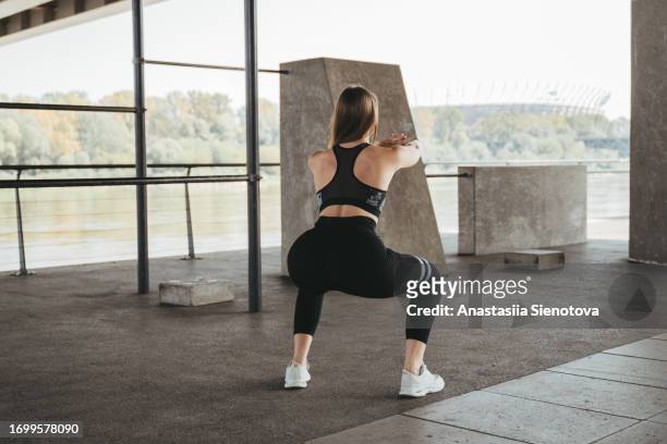 female athlete workout outdoors, rear view - hockend stock-fotos und bilder
