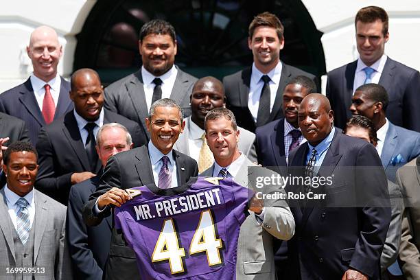 President Barack Obama holds up a jersey given to him by head coach John Harbaugh after welcoming members of the National Football League Super Bowl...