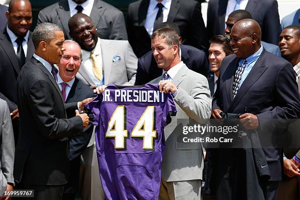 President Barack Obama holds up a jersey given to him by head coach John Harbaugh and general manager Ozzie Newsome after welcoming members of the...