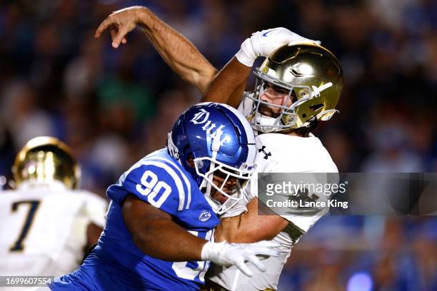 DeWayne Carter of the Duke Blue Devils hits Sam Hartman of the Notre Dame Fighting Irish after his pass during the first half at Wallace Wade Stadium...