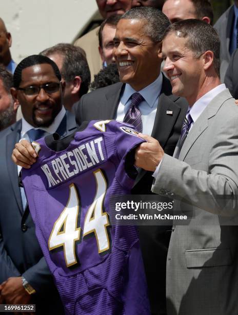 President Barack Obama holds up a Baltimore Ravens jersey given to him by head coach John Harbaugh as linebacker Ray Lewis looks on after welcoming...