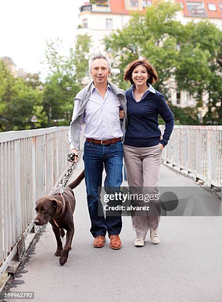 älterer erwachsener paar spaziergänge mit dem hund - man portrait full body 50's stock-fotos und bilder