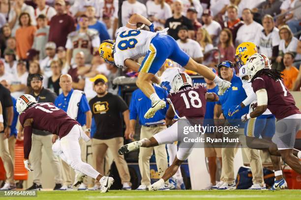 Gavin Bartholomew of the Pittsburgh Panthers leaps over Mose Phillips III of the Virginia Tech Hokies in the first half during a gameat Lane Stadium...