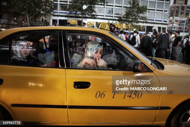 Veiled women leave in a taxi as they flee clashes between protesters and riot police during a demonstration in the central Kizilay square in Ankara,...