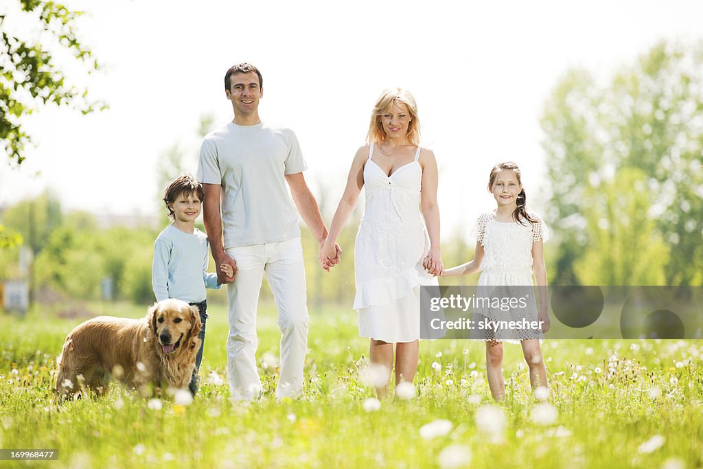 Cheerful family standing with dog in a park.